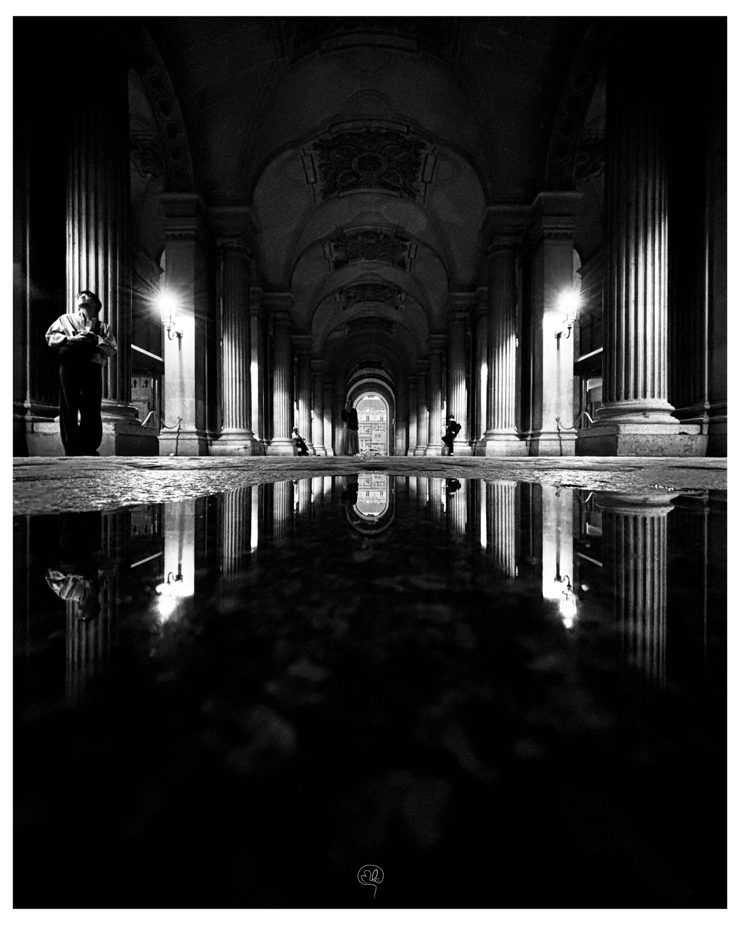 Longue perspective d'arcades éclairées et reflétées dans une flaque